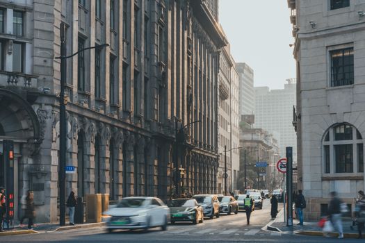 Traffic and pedestrians navigate a bustling downtown street lined with historic buildings.