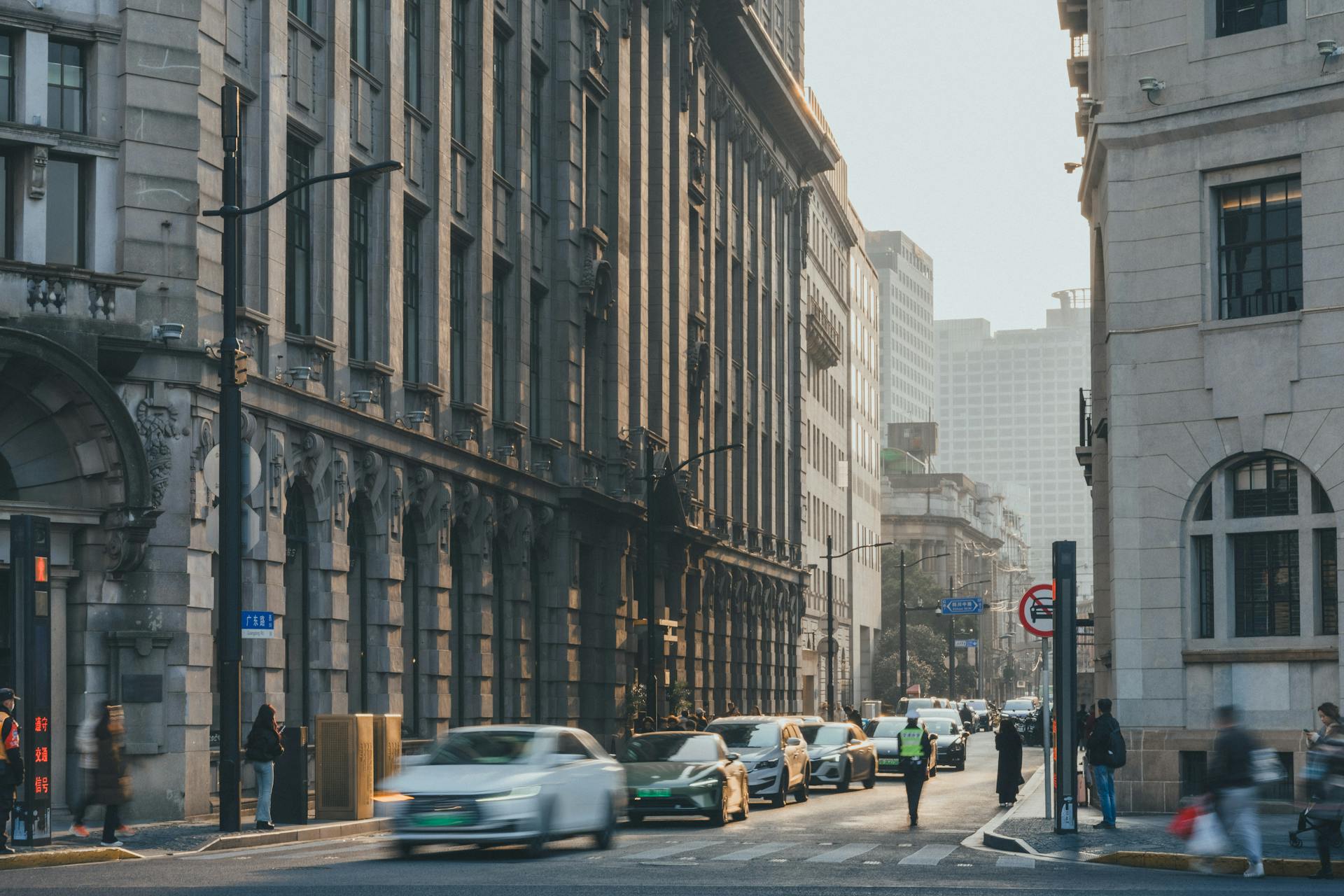 Traffic and pedestrians navigate a bustling downtown street lined with historic buildings.