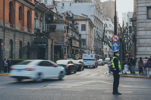 Free An urban street bustling with cars and people, featuring a traffic officer directing vehicles in a vibrant cityscape. Stock Photo