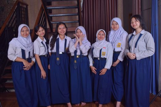 Seven teenagers in school uniforms posing happily indoors, showcasing friendship. - Fotografer Sidoarjo