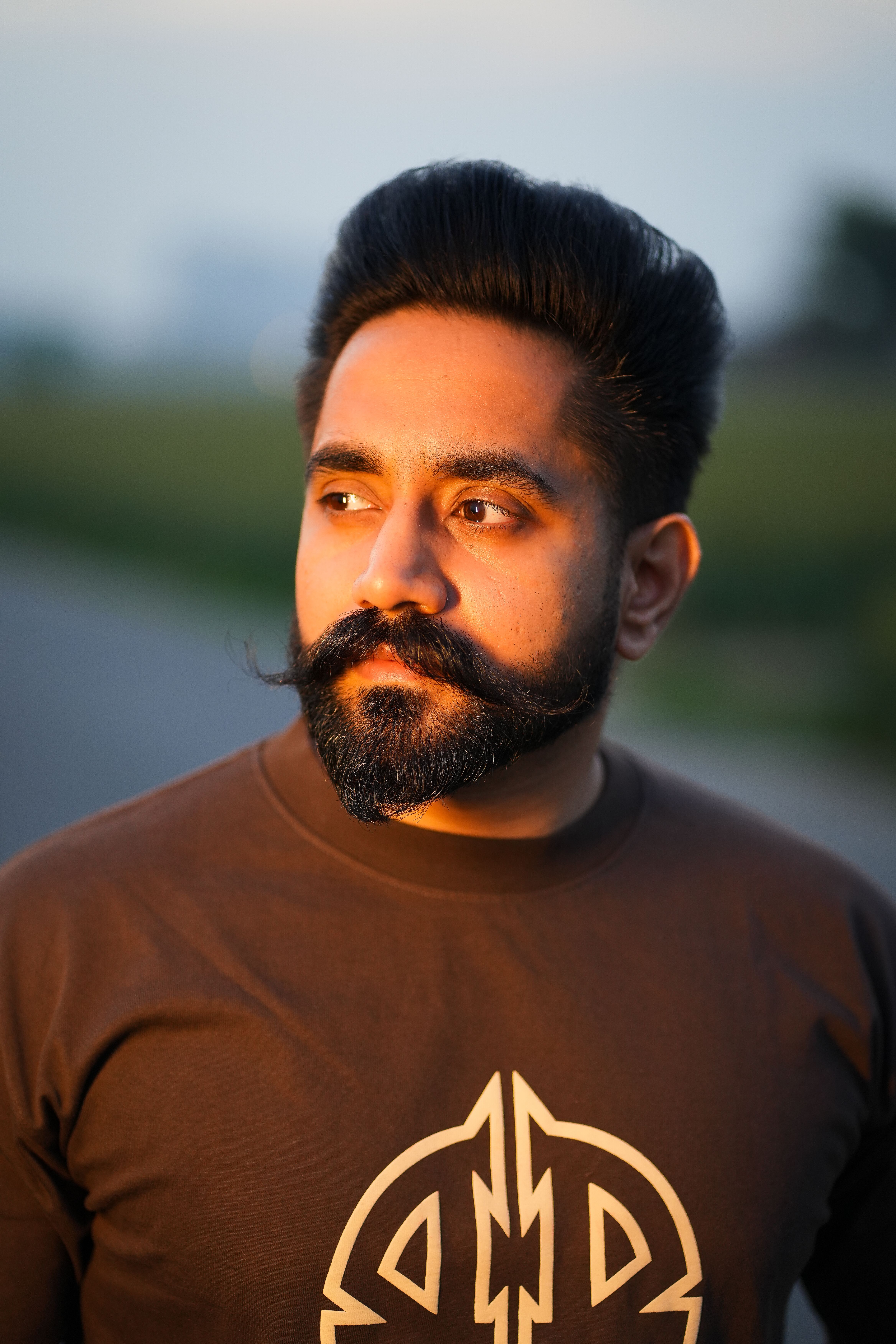 Casual portrait of a bearded man with stylish hair outdoors in soft evening light.