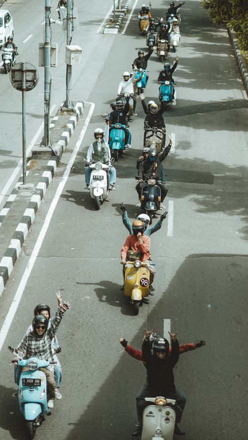 Free A group of friends riding Vespas on a sunny street in East Java, Indonesia, enjoying a fun day out. Stock Photo