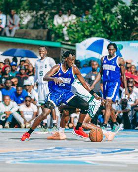 Players compete fiercely in an urban outdoor basketball match, showcasing athleticism and teamwork.