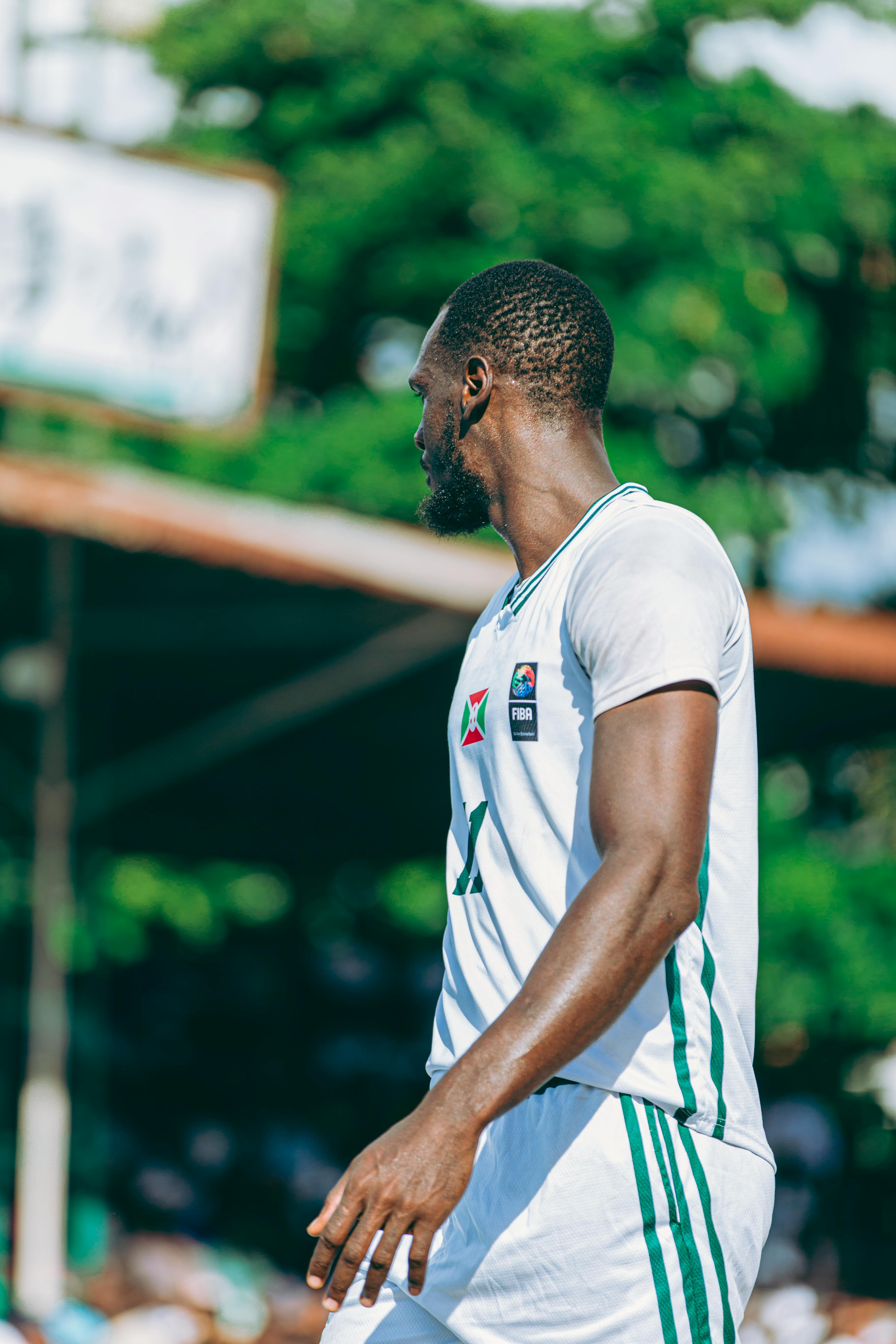 A basketball player in a white jersey outdoors during a game.