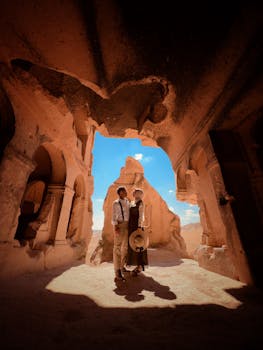 A couple standing in an ancient cave in Cappadocia, Turkey, admiring the view.