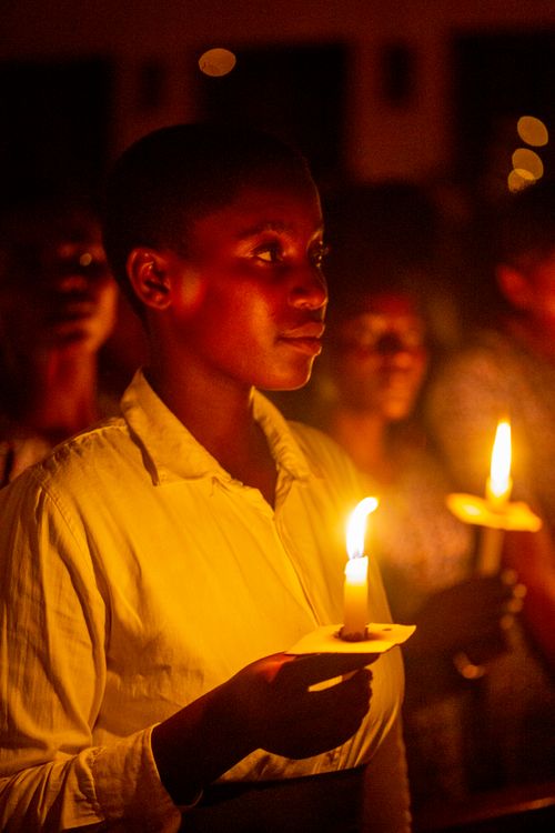 Free Peaceful candlelight vigil scene with soft warm lighting highlighting participants in a dark setting. Stock Photo