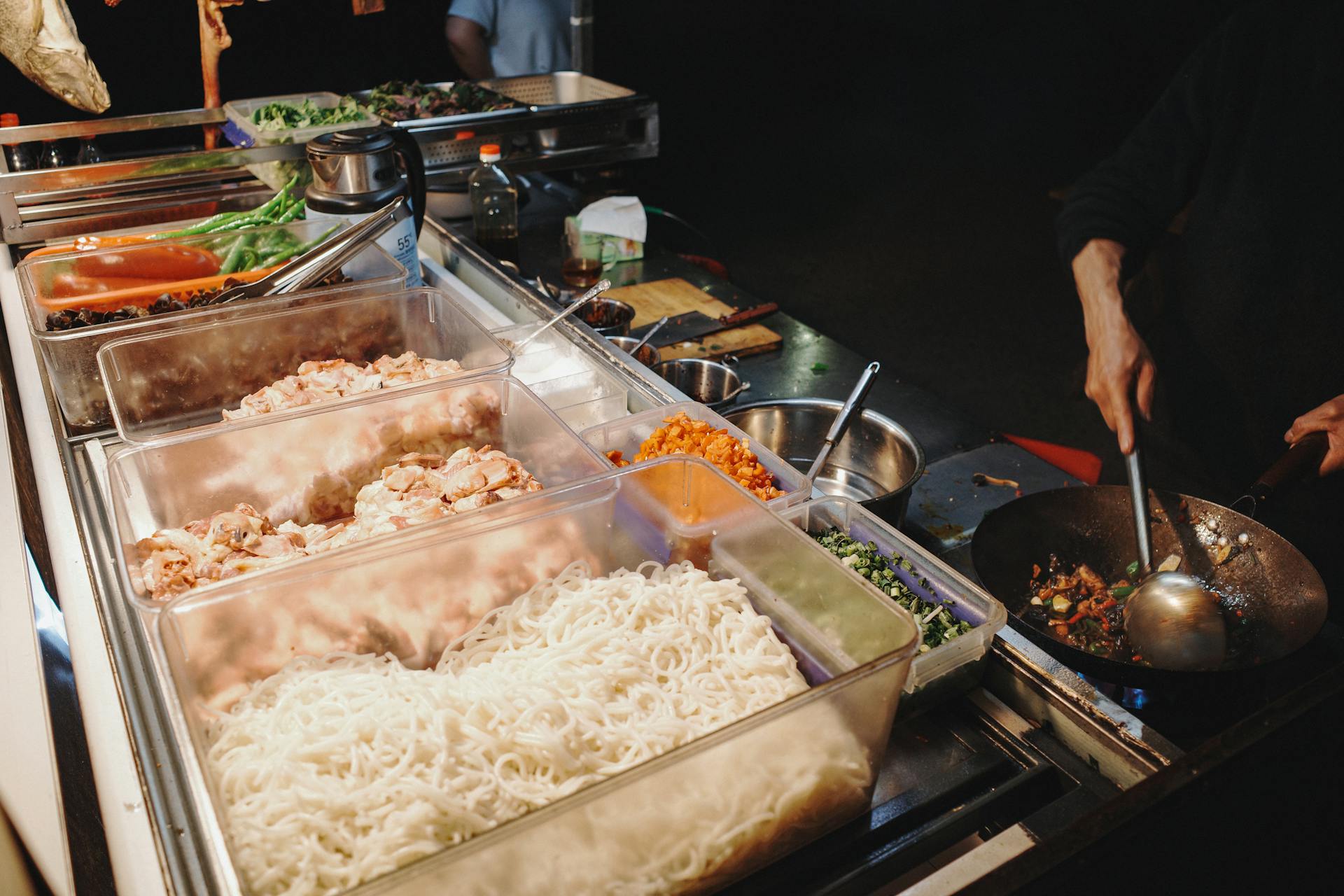 A vibrant street food stall showcasing a variety of fresh ingredients and dynamic cooking scene.