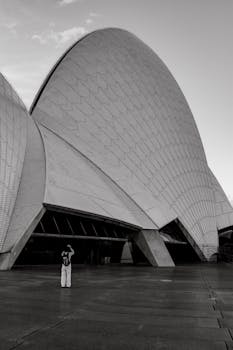 A monochrome capture of the iconic Sydney Opera House with a lone visitor.