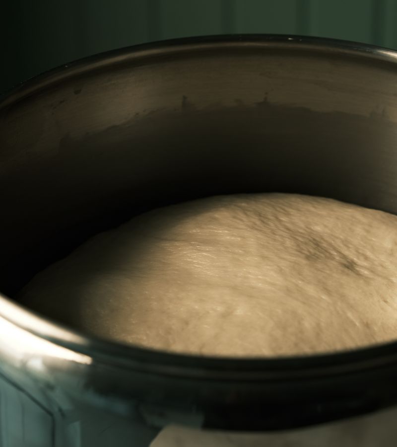 Close-up of bread dough rising in a metal bowl, ready for baking.