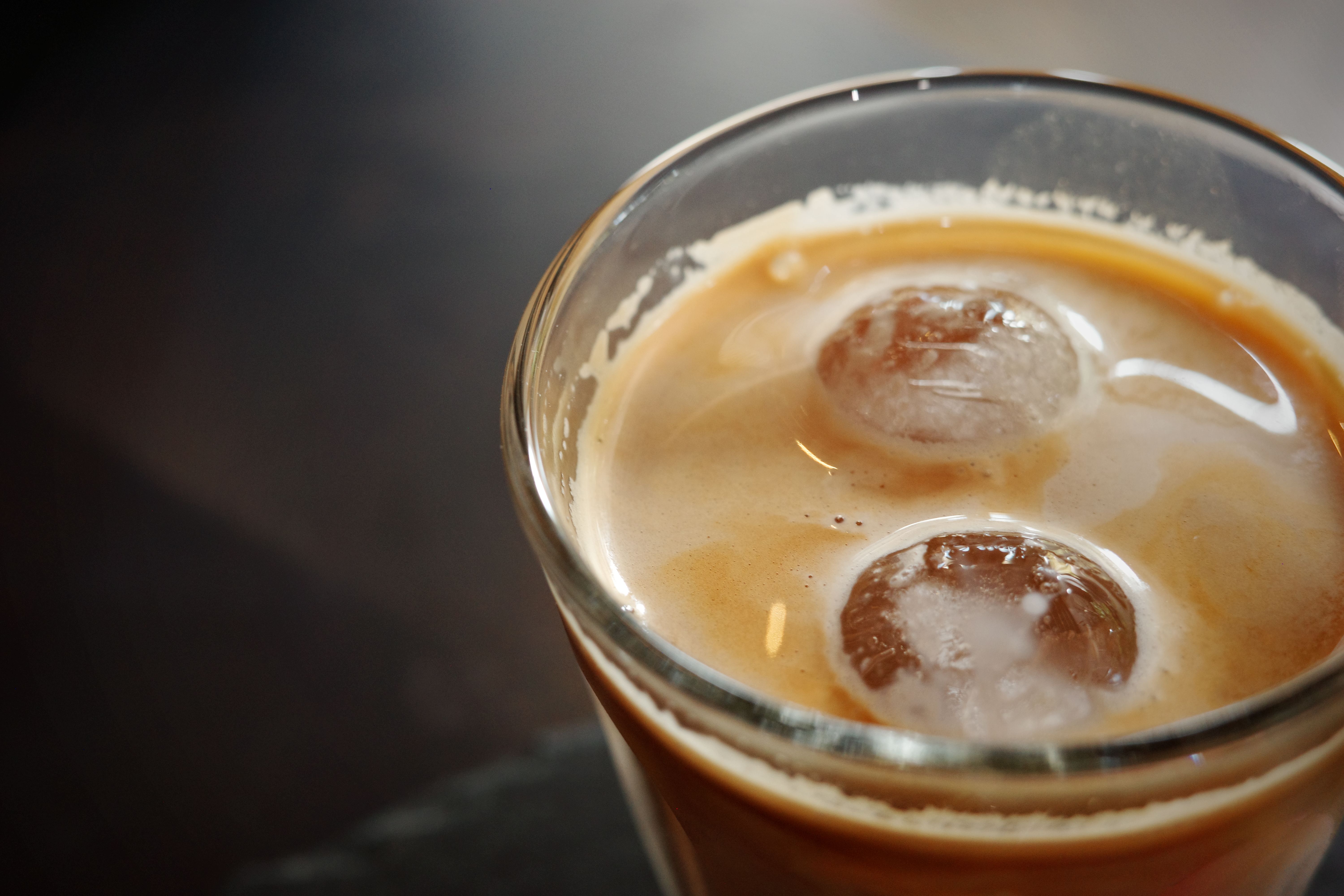 Close-up of a refreshing iced coffee with ice cubes served in a glass. Perfect for warm days.