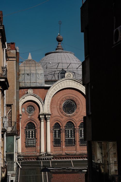 Free Elegant historic building with a prominent dome and decorative facade nestled in an urban alleyway. Stock Photo