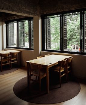 Warm, inviting café interior with wooden tables and chairs by open windows.