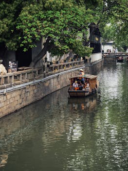 A tranquil boat ride on a narrow canal flanked by historic architecture and lush greenery.