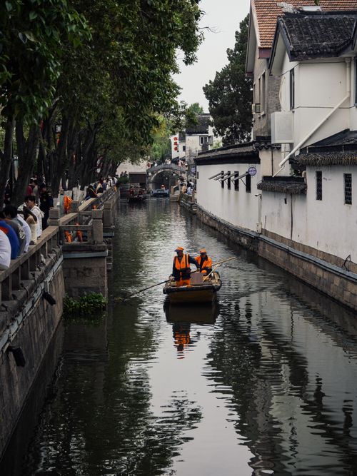Free Workers clean a canal in a historic city with traditional architecture, creating a tranquil scene. Stock Photo