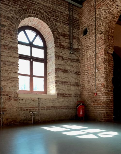Free Sunlight casts geometric patterns on the floor of a rustic brick room with an arched window. Stock Photo