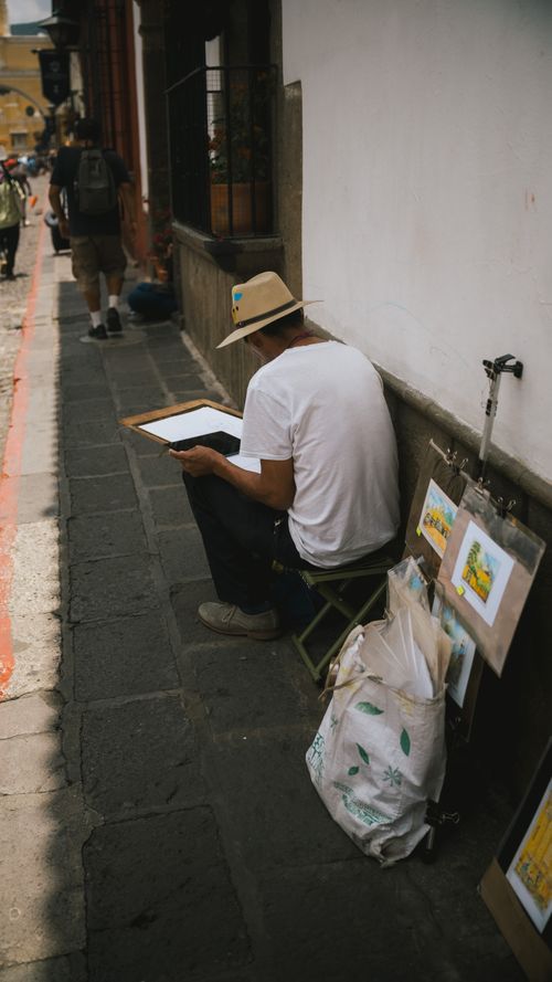 Free A street artist in Antigua Guatemala creating art outdoors, showcasing local culture. Stock Photo