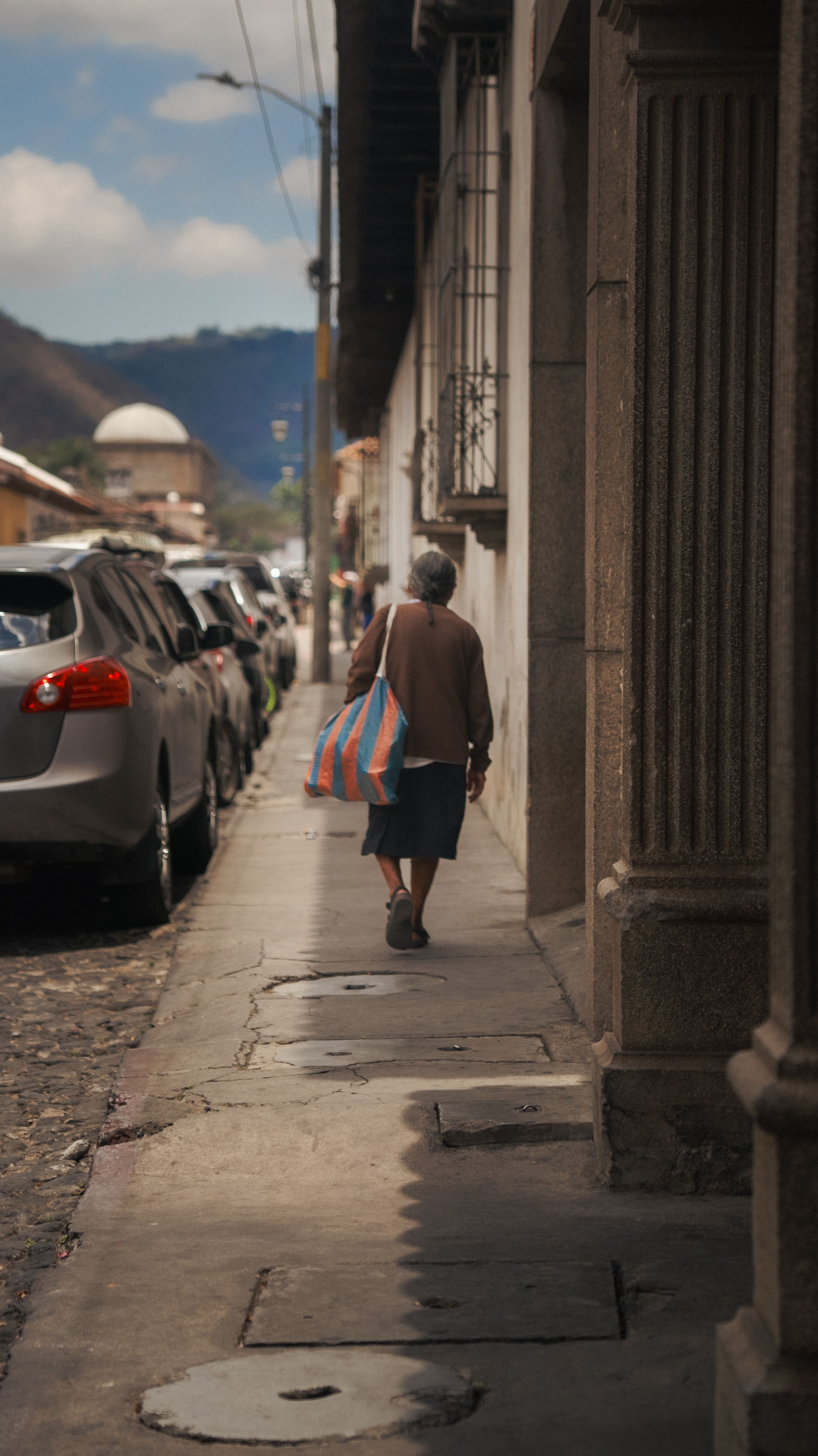 Una mujer camina por una calle histórica en Antigua Guatemala, capturando la vibrante cultura y arquitectura.