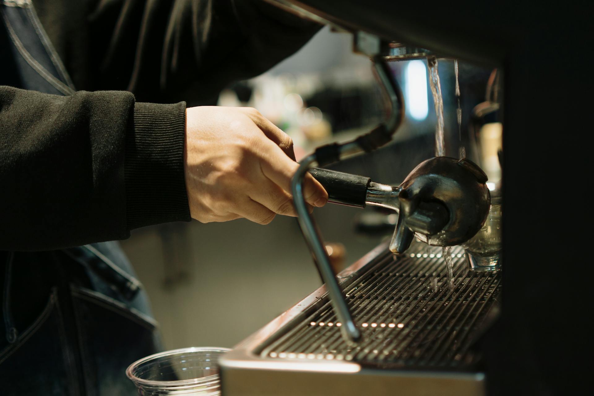 A barista pulls an espresso shot in a coffee machine, showcasing precision and skill.