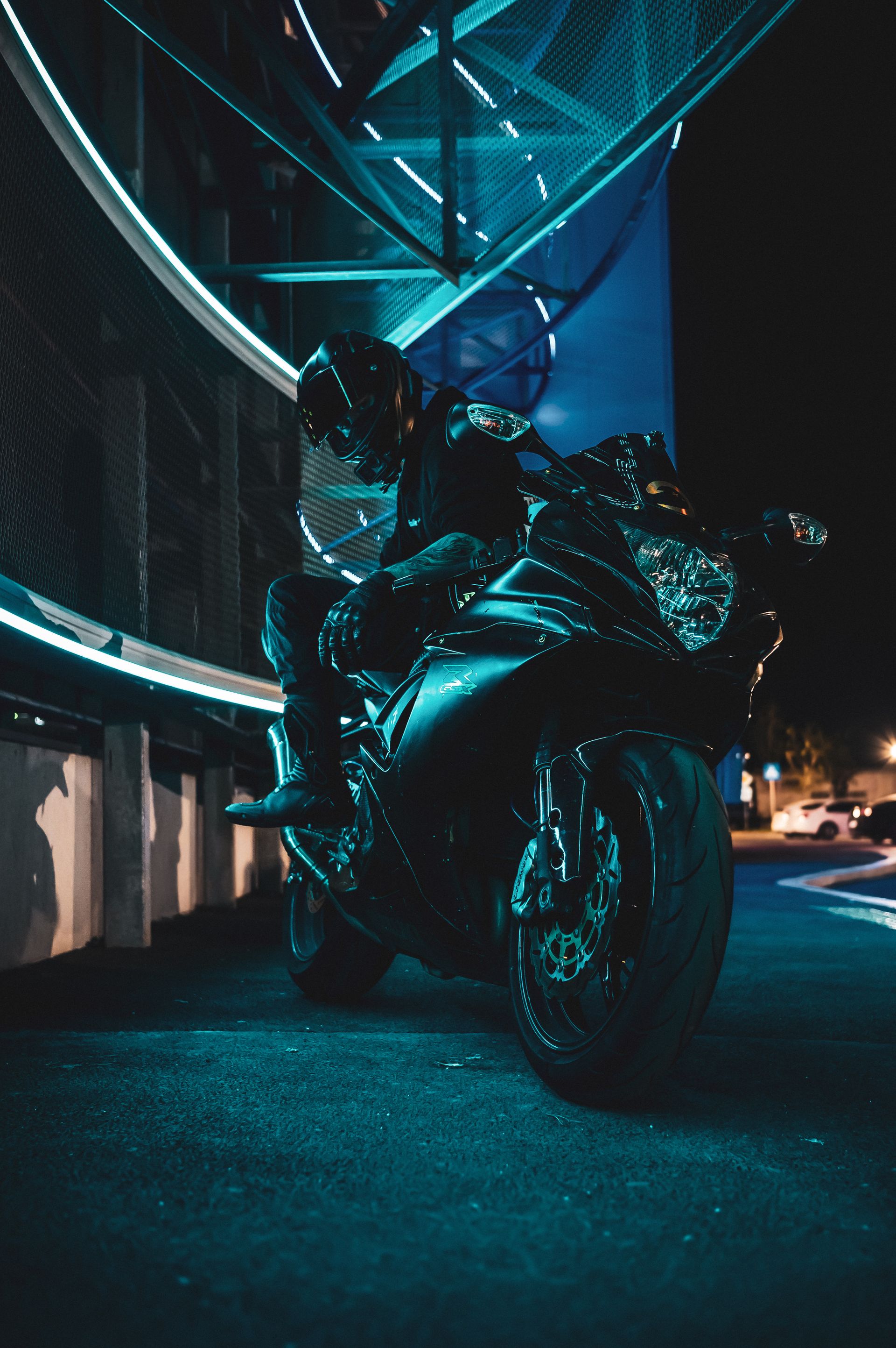 Motorcyclist on a sleek sports bike under neon lights in a modern city at night