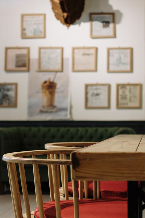 Free A cozy cafe interior featuring stylish wooden chairs and framed art on the walls. Stock Photo