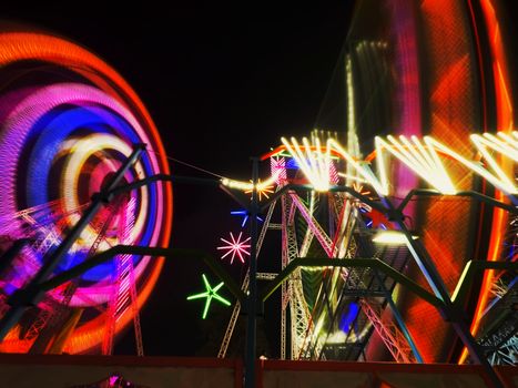 Dazzling lights and colors of amusement park rides at night create a festive atmosphere.