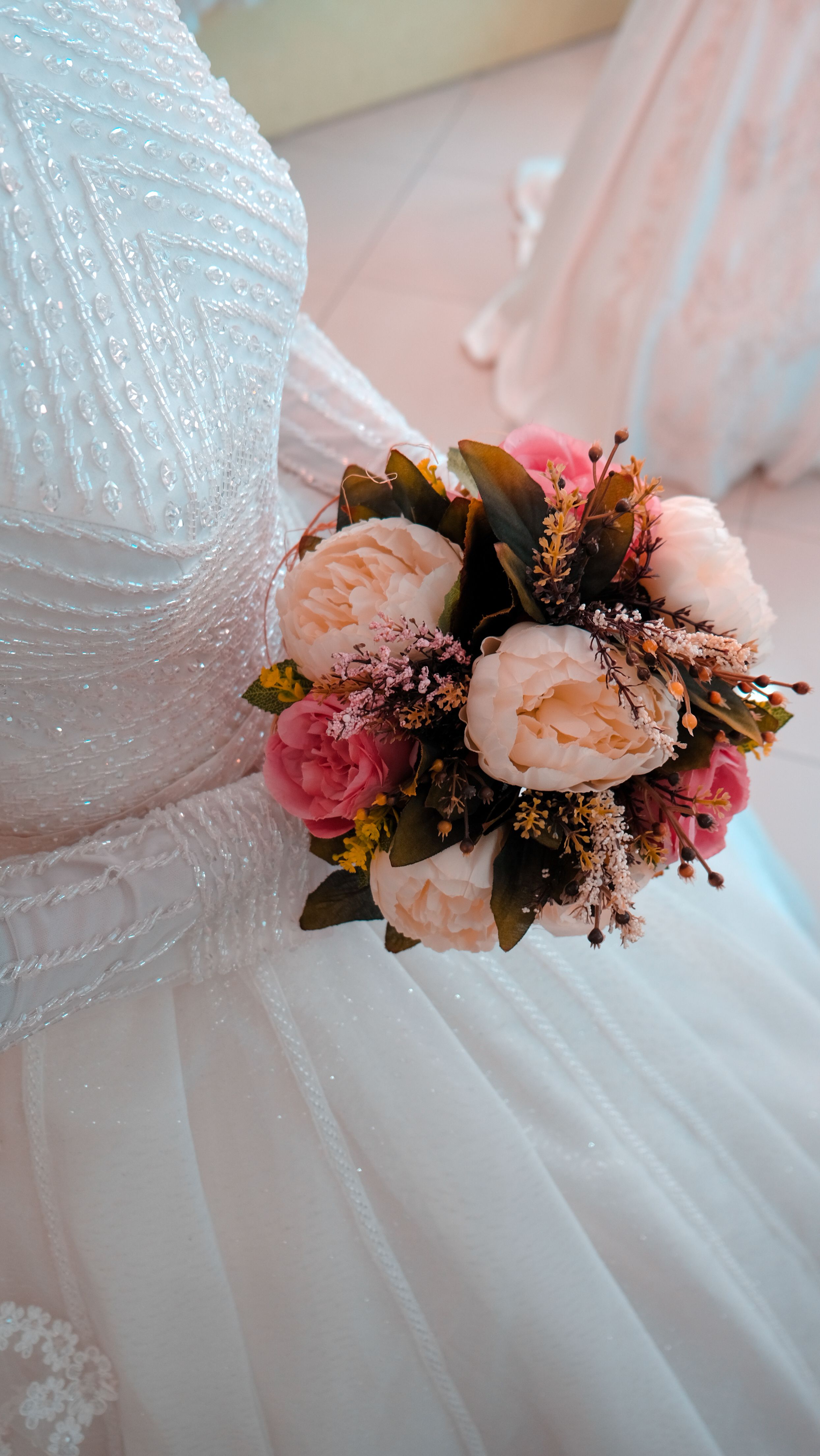 Close-up of a bride holding a beautiful bouquet with pink and white flowers.
