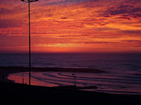 Vibrant sunset over the ocean with dramatic sky and pink-orange hues.