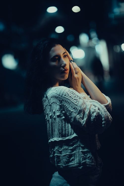 Free Dramatic nighttime portrait of a woman in a stylish knitted sweater under city lights. Stock Photo