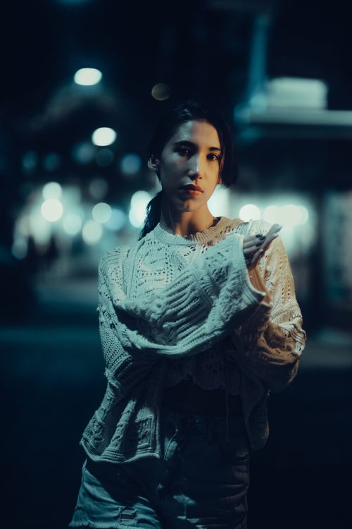 Free Portrait of a young woman wearing a knit sweater at night in a city setting. Stock Photo