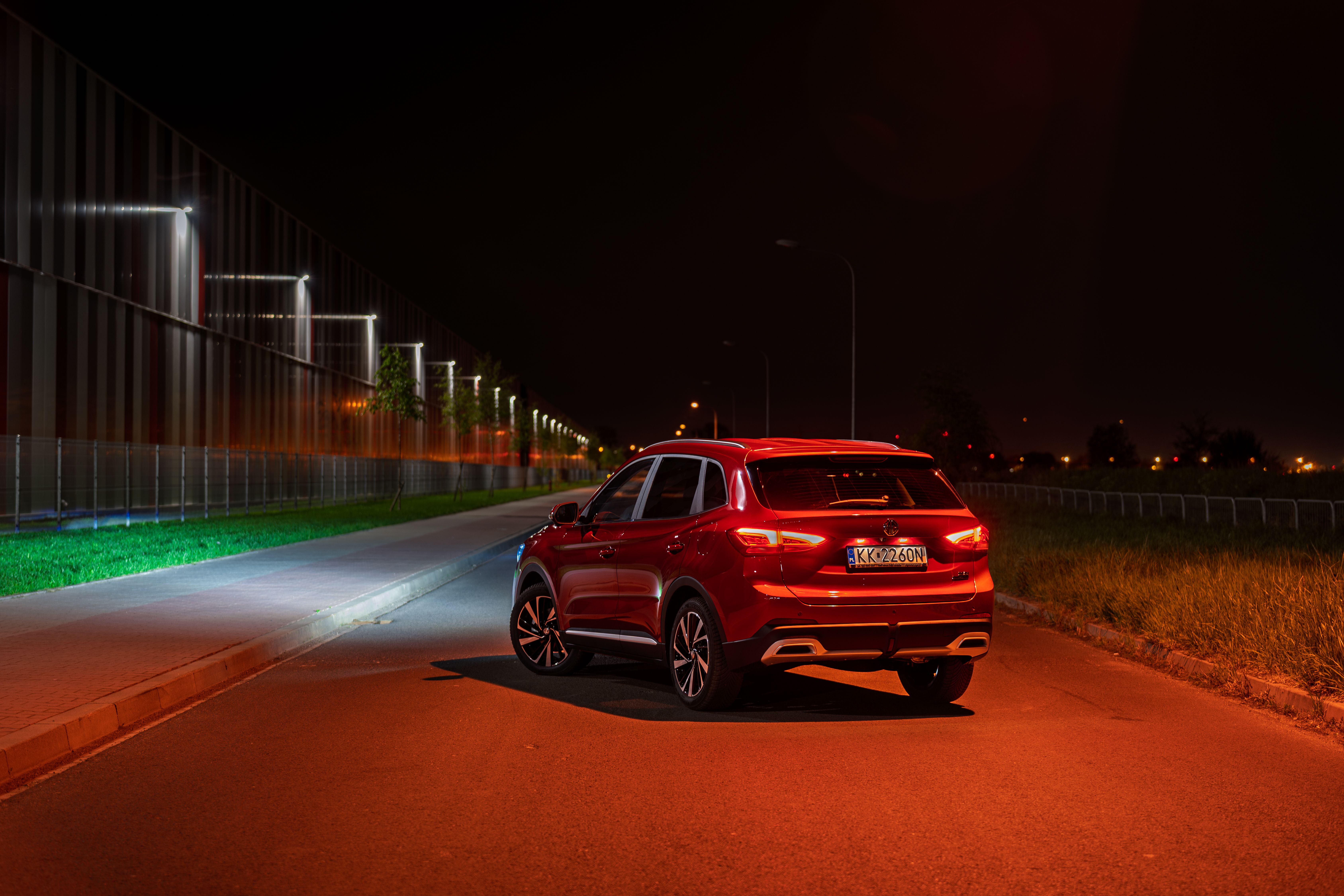 Red SUV parked on a road at night under streetlights.