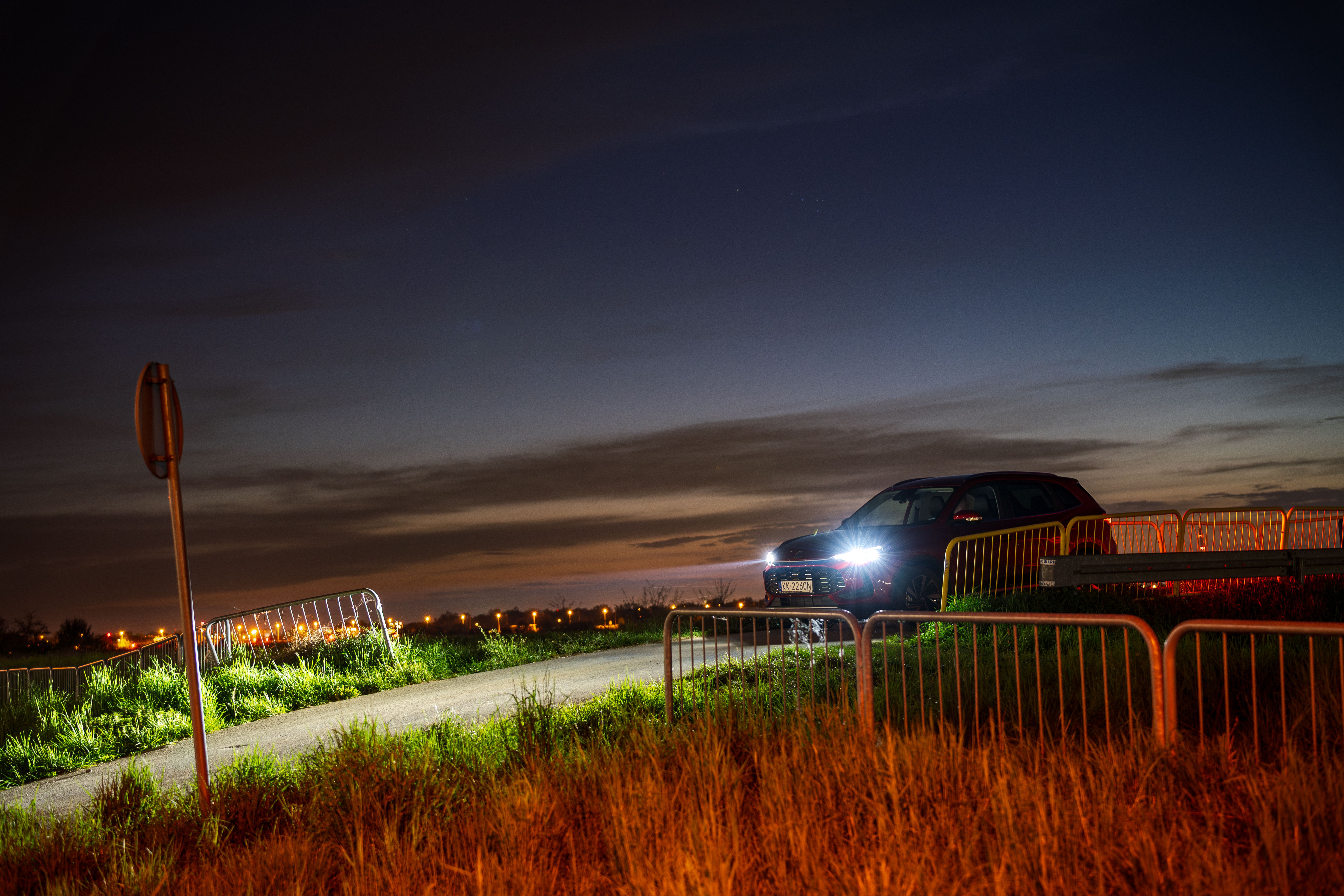 A dramatic night photograph of a car with headlights on, captured in Kokotów, Poland.