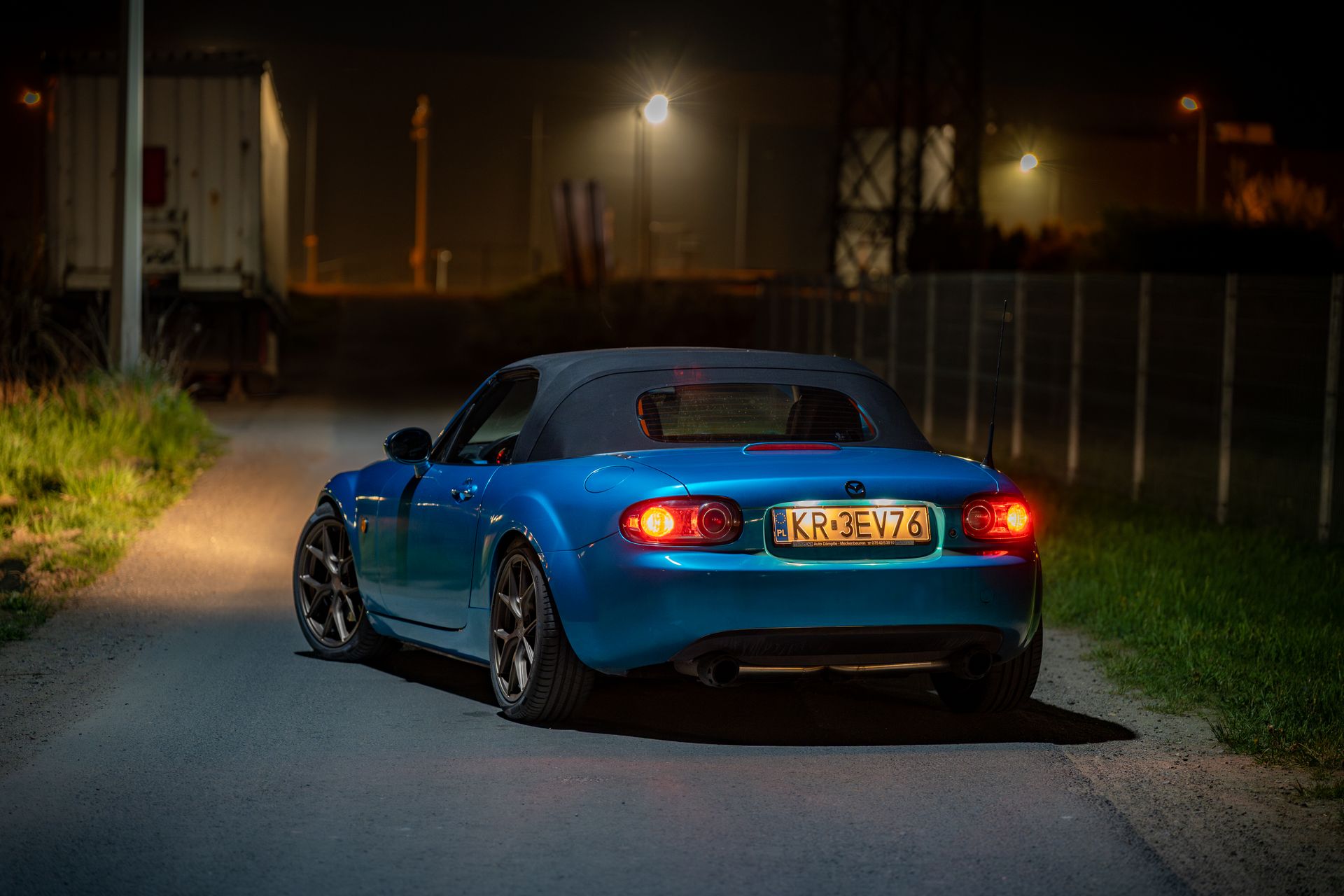 Stylish blue sports car parked on a dimly lit road in Kokotów, perfect for automotive enthusiast content.