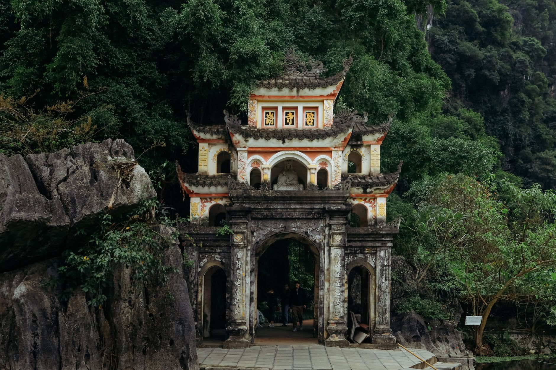 Storico cancello del tempio tra la fitta vegetazione a Ninh Binh, Vietnam, che mostra una splendida architettura.