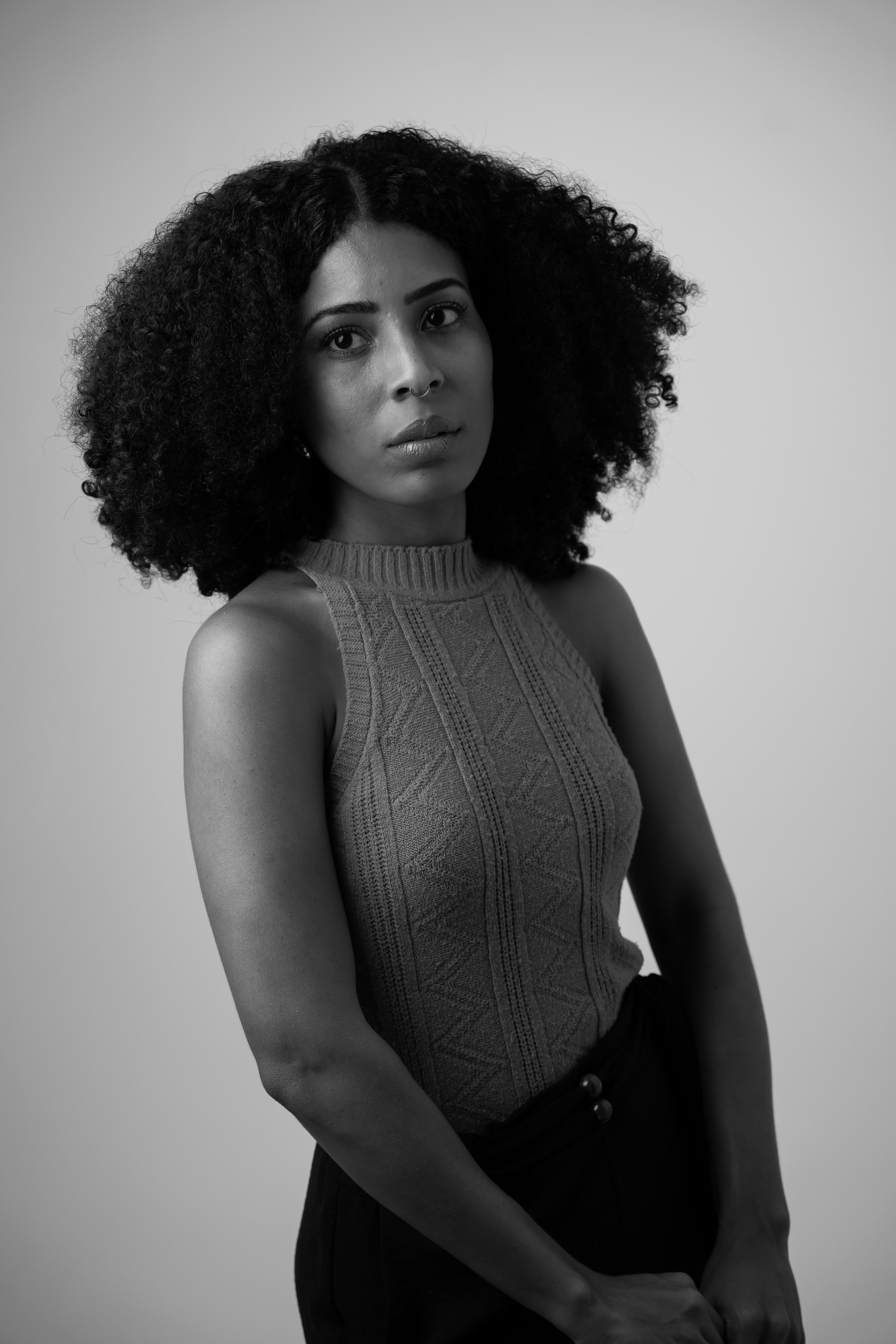Striking black and white portrait of a woman with curly hair, deep in thought.