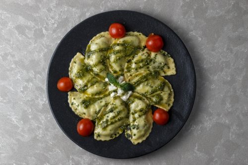 Free Delicious Italian ravioli topped with pesto sauce, garnished with cherry tomatoes and basil. Stock Photo