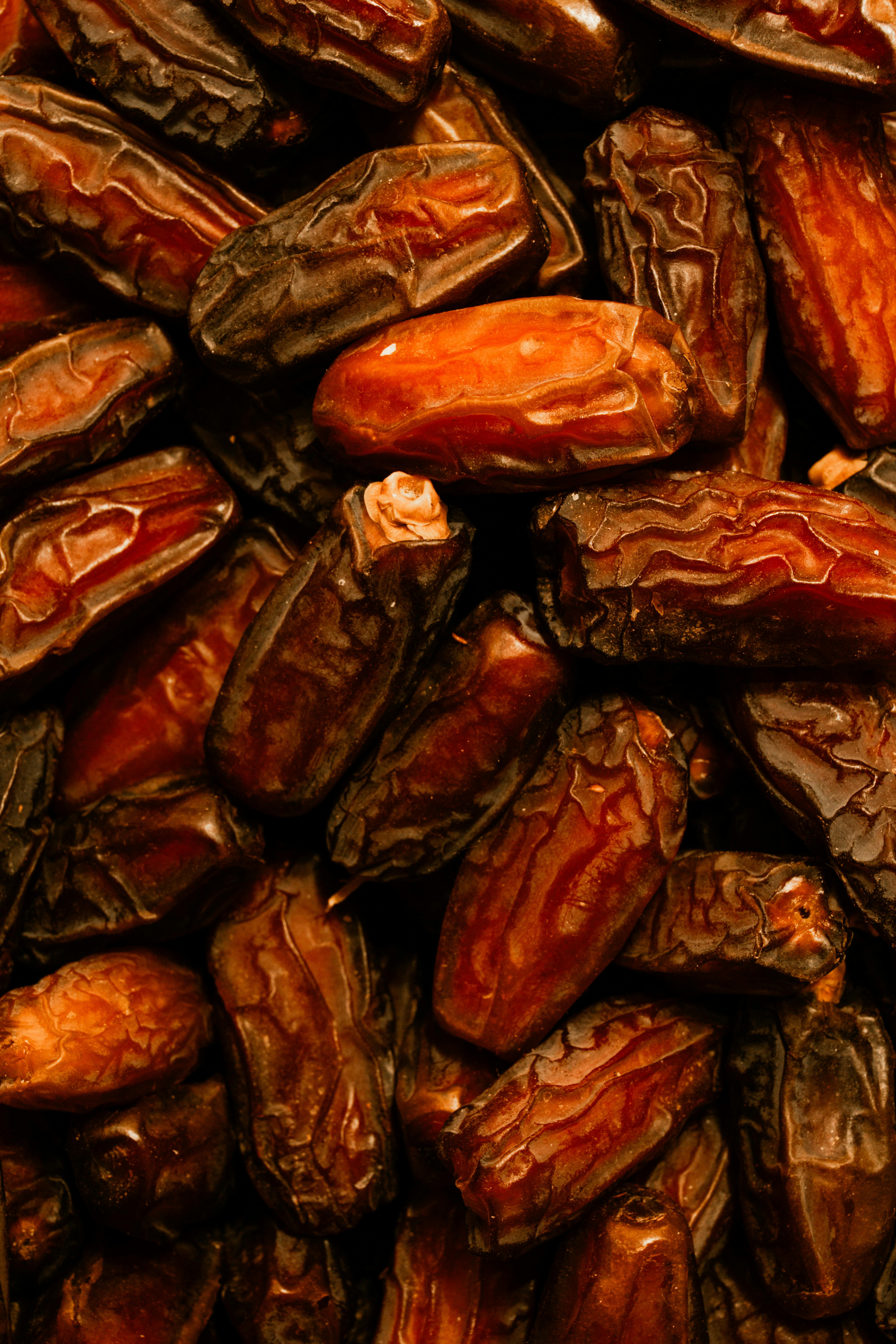 A detailed view of fresh, organic dates with a rich, warm tone showcasing texture and natural color variations.