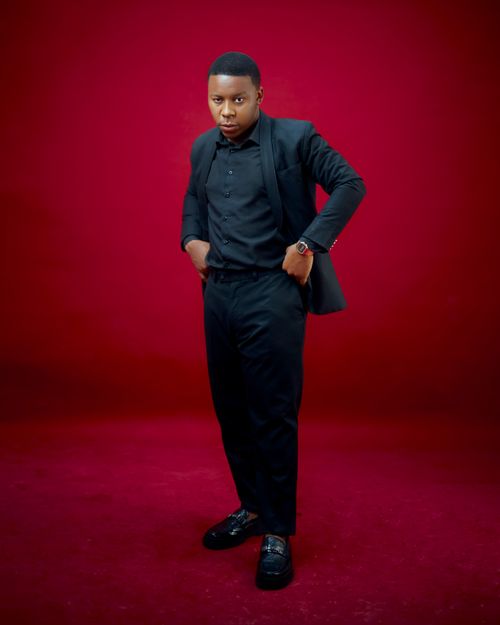 Free Portrait of a confident man in a black suit standing against a rich red backdrop. Stock Photo