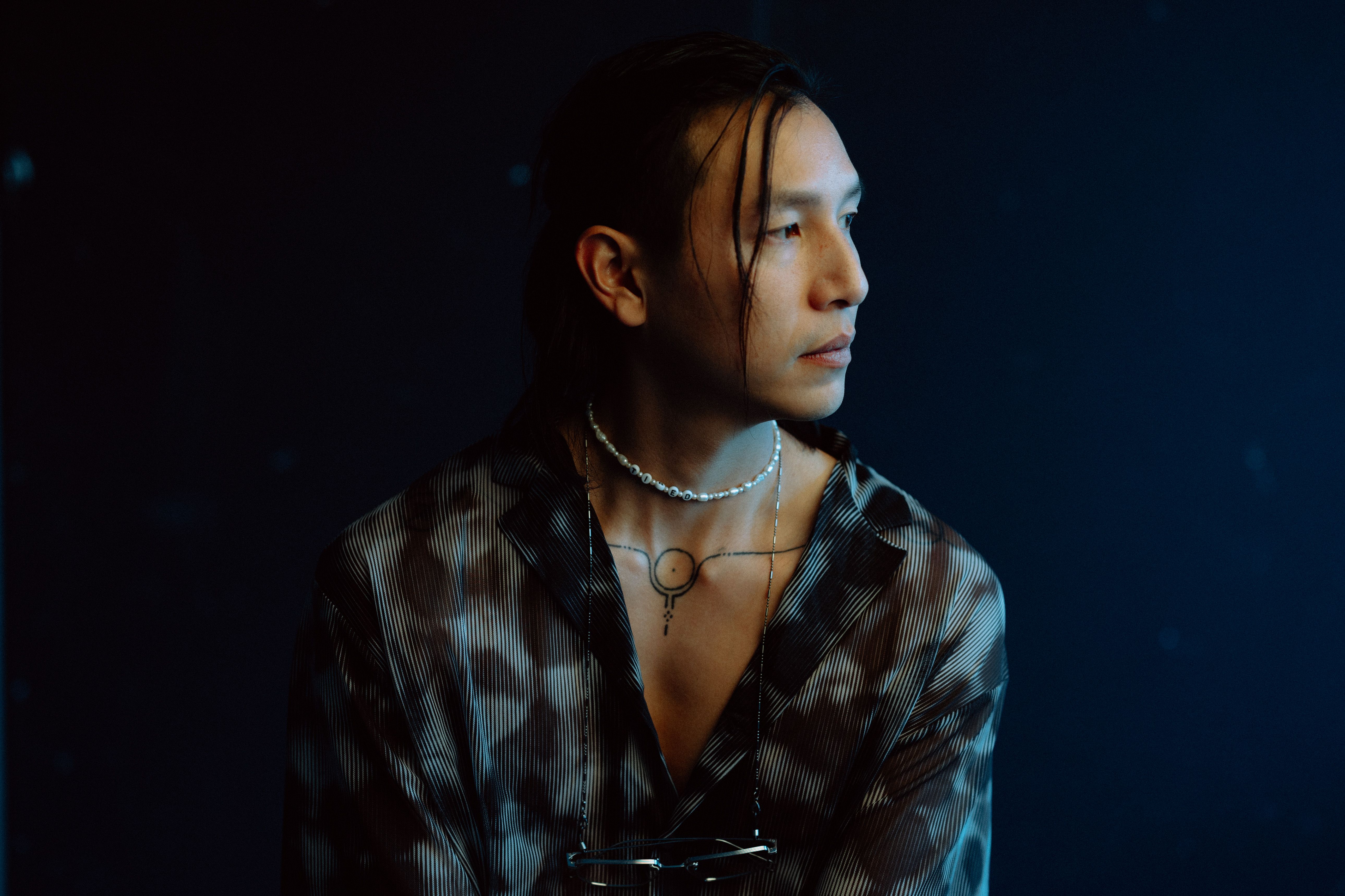 Fashionable portrait of a man with jewelry in a moody Berlin studio setting.