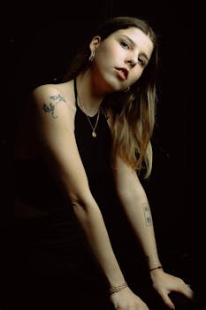 Elegant portrait of a woman with tattoos, showcasing artistic style and moody lighting in Berlin.