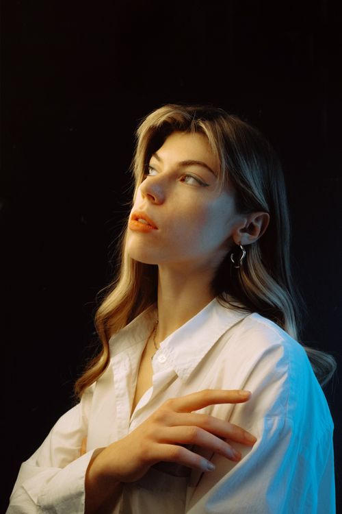 Free Elegant studio portrait of a woman in a white shirt with soft lighting and dramatic shadows. Stock Photo