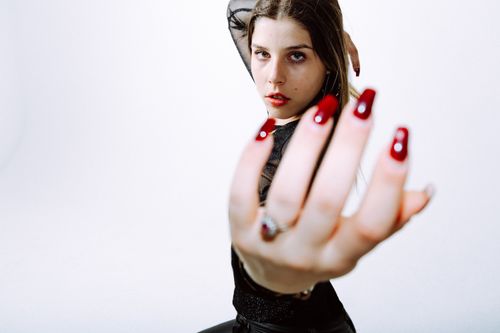 Free Close-up portrait of a fashionable woman in a Berlin studio, highlighting her red manicure. Stock Photo