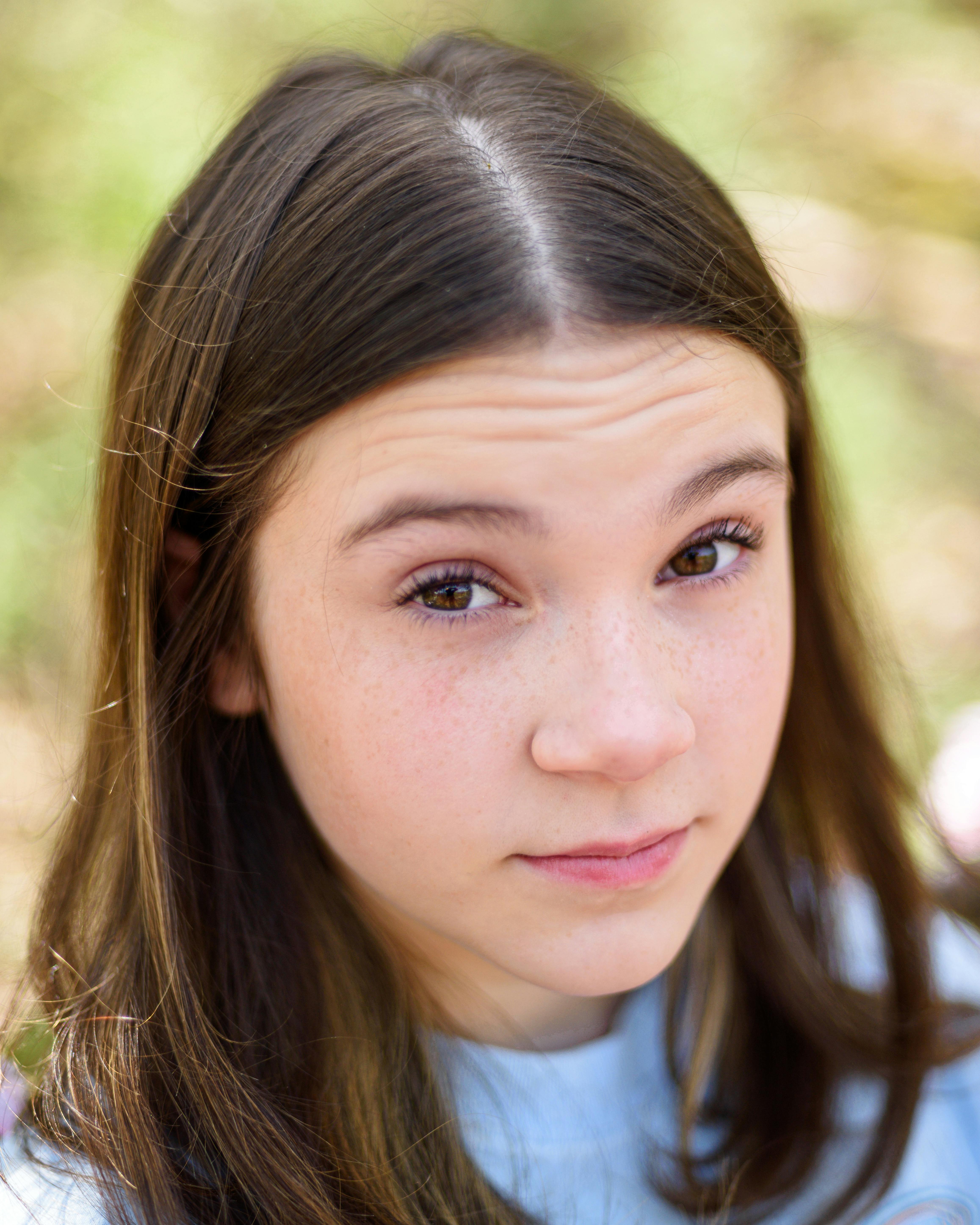 Close-up portrait of a teenage girl outdoors with soft focus background.