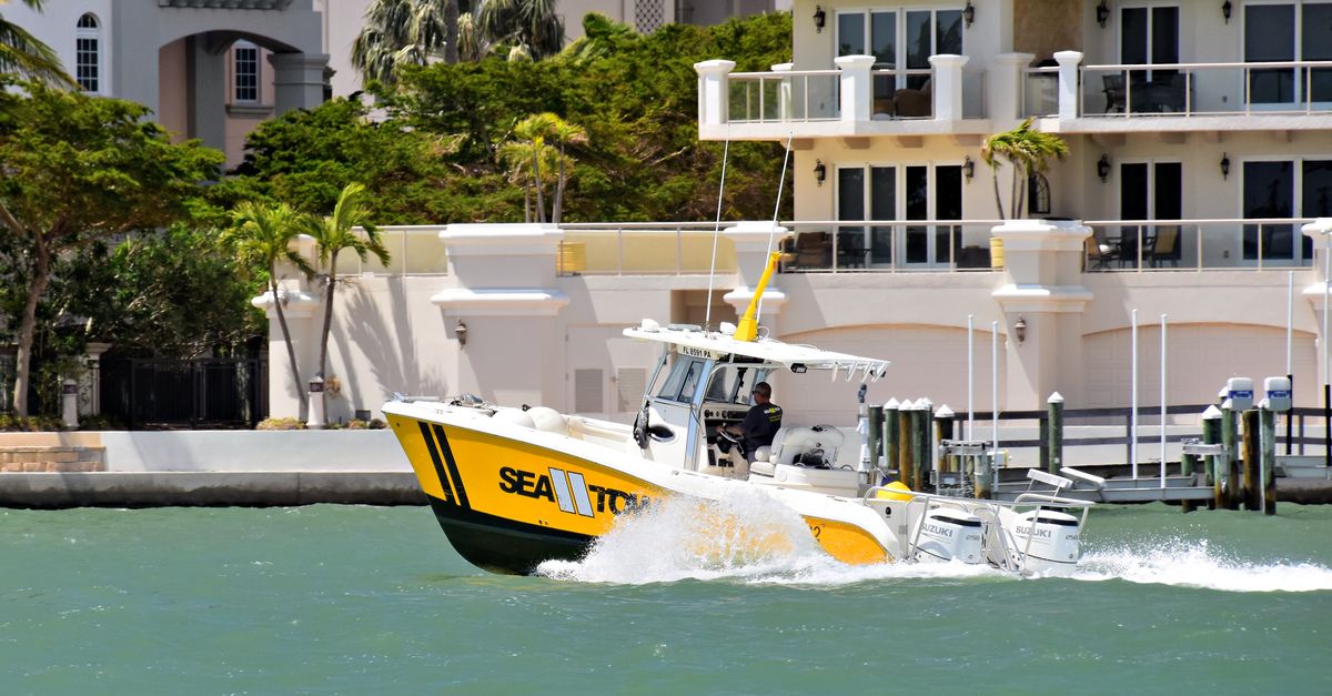 A vibrant speedboat cutting through Sarasota Bay with waterfront buildings in the backdrop.