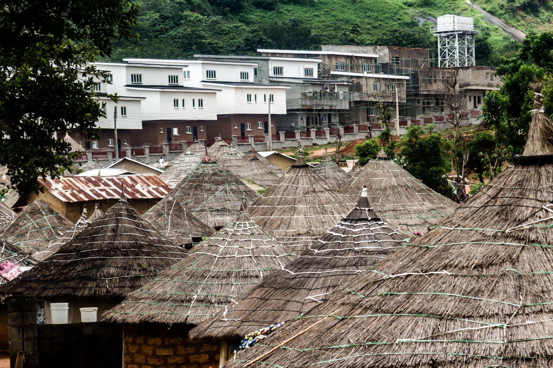 Contrast of thatched huts and modern buildings in Abuja, Nigeria.