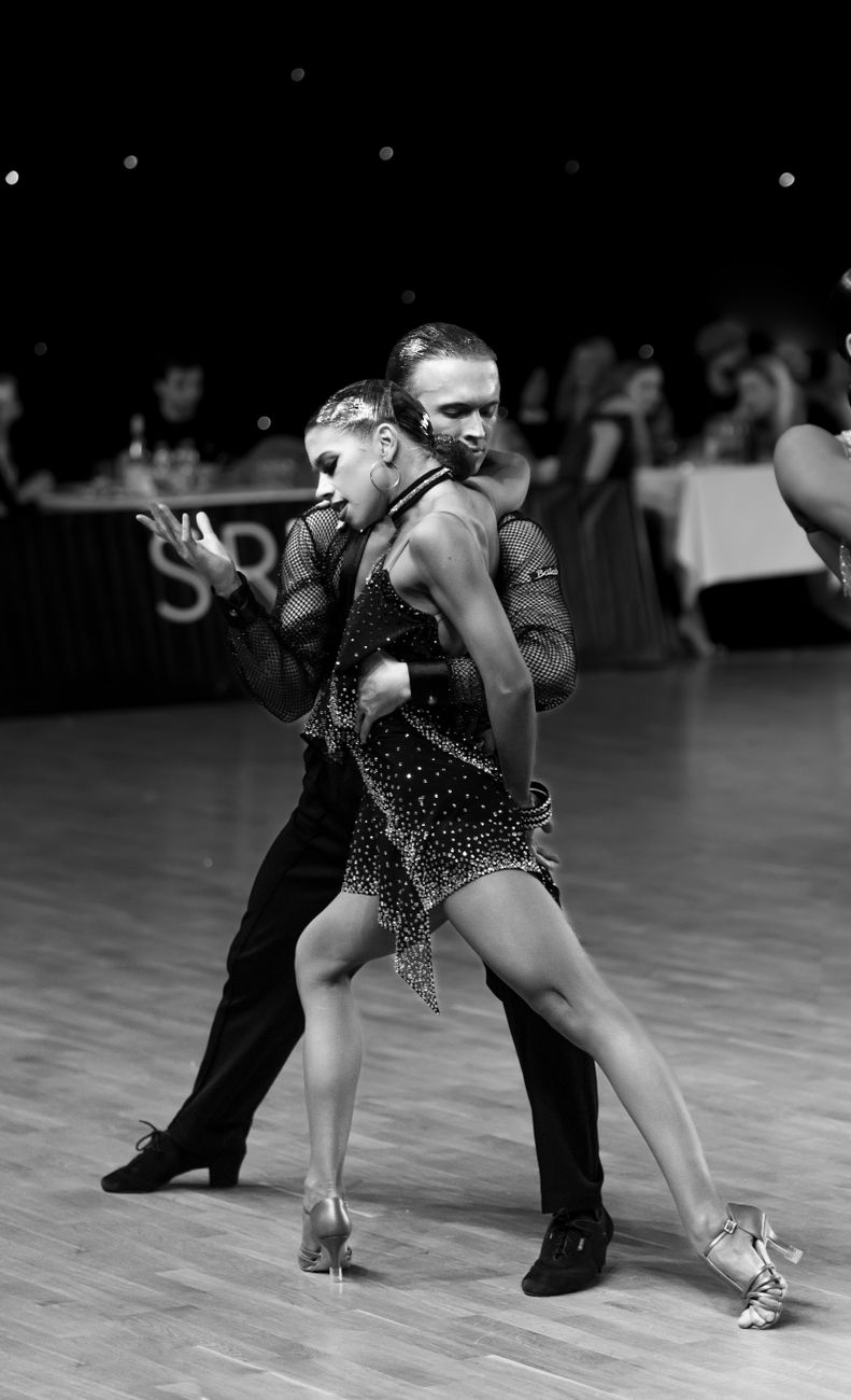 A couple practicing partner dance styles in an elegant ballroom studio.