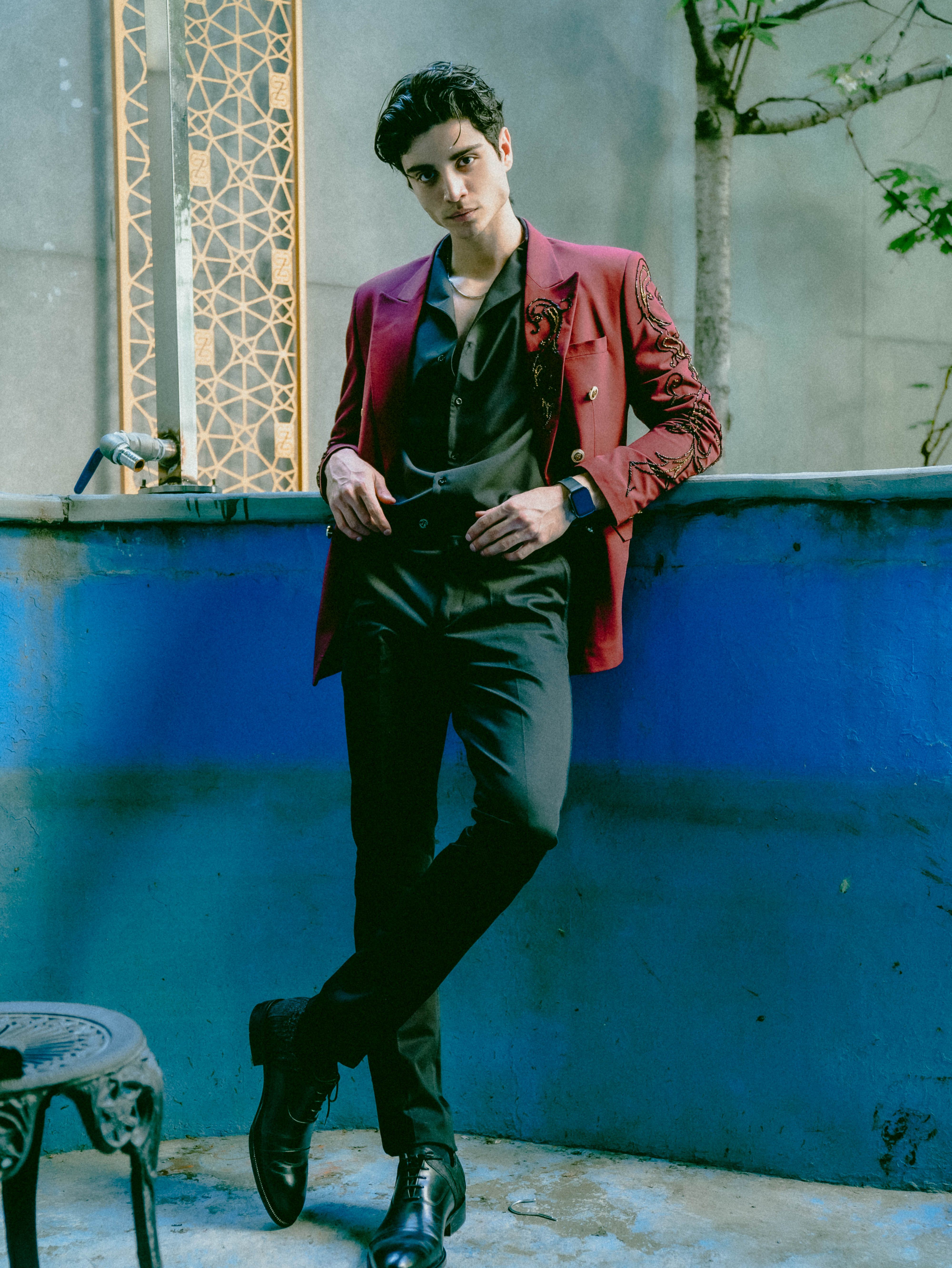 Fashionable man in a red jacket posing in an urban setting, showcasing contemporary style.