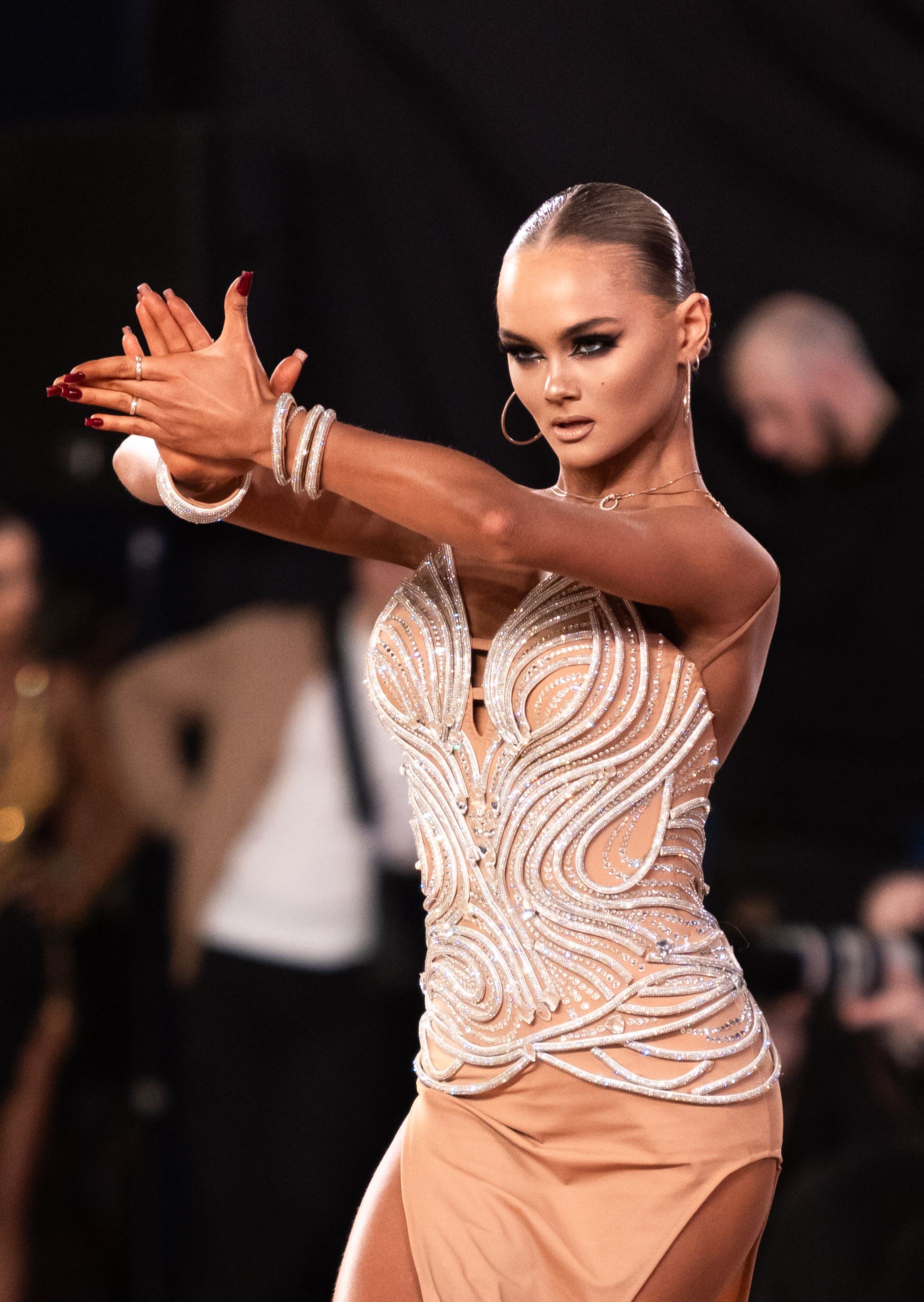 A glamorous female dancer performing passionately in a detailed dress during a dance competition.