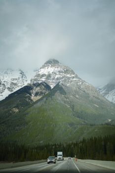 Stunning view of snow-capped mountain with cars and trucks on a winding road.