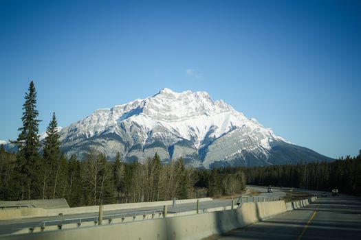 Captivating snow-capped mountain scene captured from a highway in Banff National Park during winter.