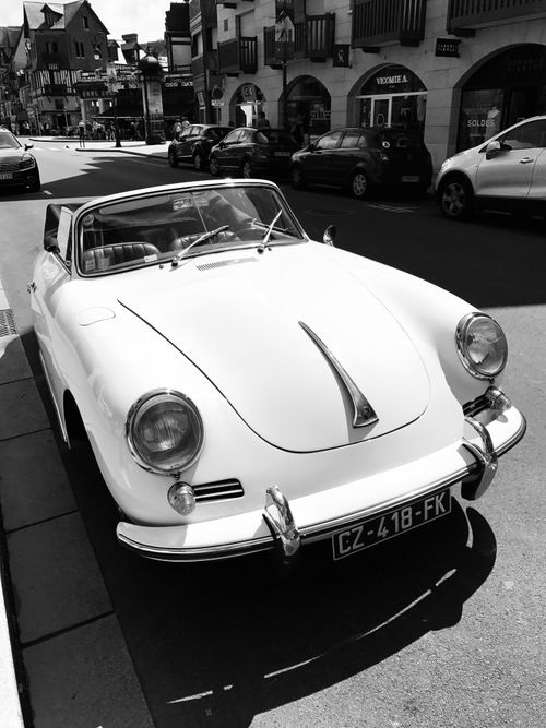 Free Black and white photo of a vintage white convertible parked on a European street. Stock Photo